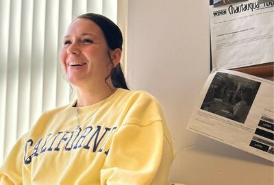 A college student smiles while talking in a campus office.