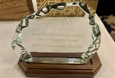 A glass award with wood base sitting on a table.
