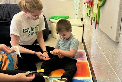 A child plays with an adult in an occupational therapy setting.