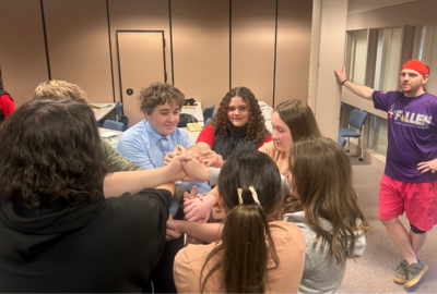 Students close together hold hands during a team-building activity.