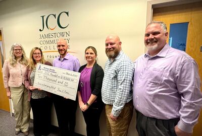 Six people together with two holding a large check worth $10,000.