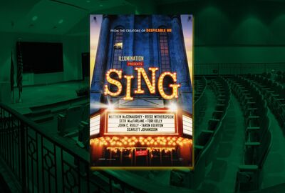 Poster for the animated movie Sing displayed in front of a dimly lit auditorium with tiered seating. The poster features bright marquee-style lettering and lists voice actors including Matthew McConaughey, Reese Witherspoon, and Scarlett Johansson.