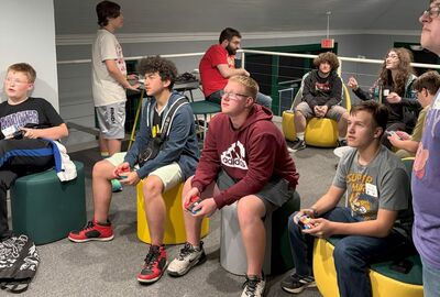 Young people hold gaming controllers while playing a video game.