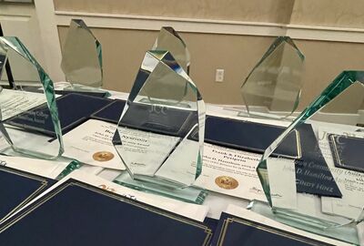 Several glass awards and certificates are displayed on a table, ready for distribution at a ceremony.