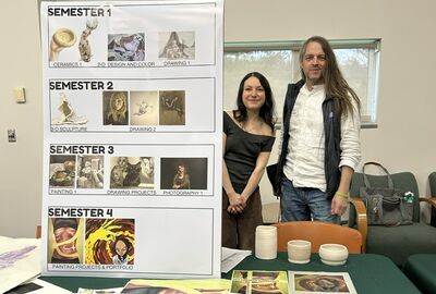 Two people stand beside a display board showing an art course sequence with images for each semester. Artworks and ceramics are on a table nearby.