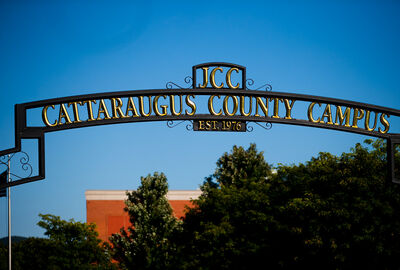 Entrance arch reading “JCC Cattaraugus County Campus, Est. 1976,” framed by trees and a blue sky on a sunny day.