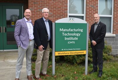 Three men stand beside a JCC Manufacturing Technology Institute sign outside a brick building, highlighting workforce development and education.
